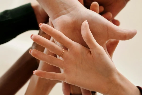 A diverse group of individuals from Value for Good joining hands in unity, symbolizing teamwork and collaboration.